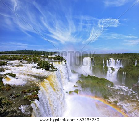 The grand Iguazu Falls on the Brazilian side. Multi-tiered cascades of water roar of lush jungle. Over boiling water swirls fine mist