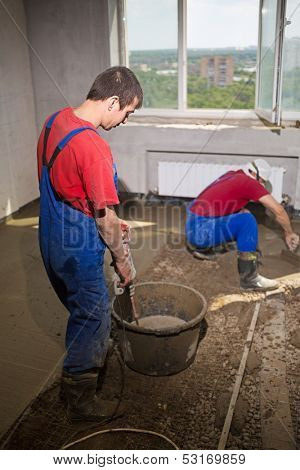 Two workers in a room poured concrete floor