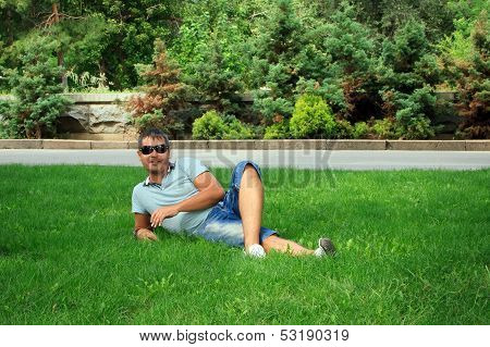 Happy Young Man Relaxing On The Green Grass