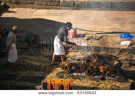 KATHMANDU, NEPAL - DEC 3, 2013: Unidentified local people during the cremation ceremony along the holy Bagmati River in Bhasmeshvar Ghat at Pashupatinath temple in Kathmandu.
