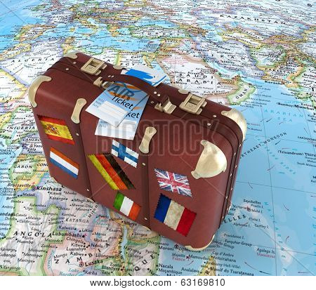 Old Suitcase With Air Ticket And Striples Flags On Blurred World Map In Background