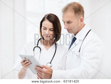 healthcare and medical and technology concept - two doctors looking at tablet pc