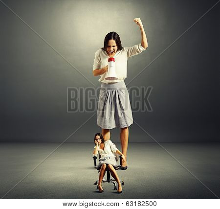 big angry businesswoman screaming at lazy woman over dark background