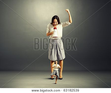 discontented businesswoman screaming at small yoga woman over dark background