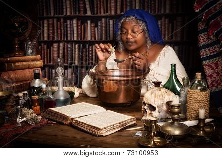Vintage alchemist adding herbs to a smoking kettle