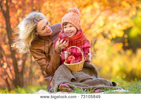 Mother and kid have pinic together in autumn park.