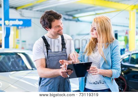 Male workshop mechanic handover car with checklist to client 