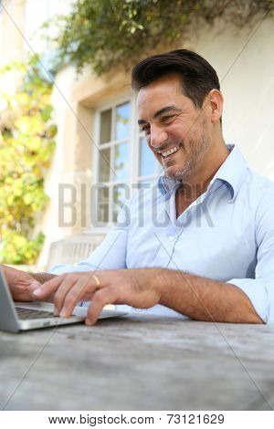 Mature man on week-end working from home with laptop