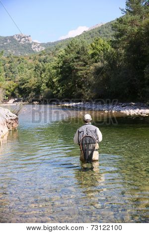 Fly fisherman flyfishing in river