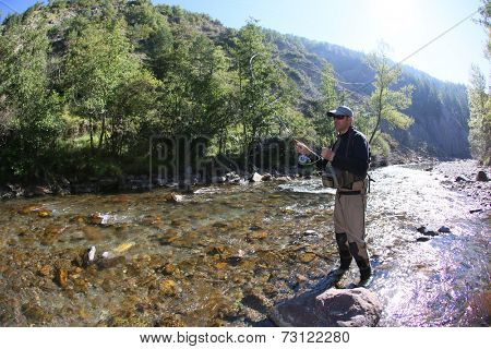 Fly fisherman using flyfishing rod in beautiful river 