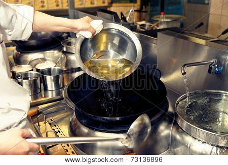 Chef is pouring cooking oil in wok, toned