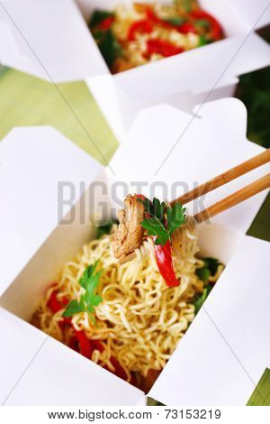Chinese noodles and sticks in takeaway boxes closeup