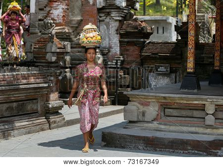 SEPTEMBER 18, 2014 - BALI, INDONESIA: A Balinese lady carries a straw basket on her head walks into the Tirta Empul Temple for ceremonial prayers.  Hinduism is the religion of the Balinese people.