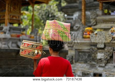 SEPTEMBER 18, 2014 - BALI, INDONESIA: A Balinese lady carries a straw basket on her head walks into the Tirta Empul Temple for ceremonial prayers.  Hinduism is the religion of the Balinese people.