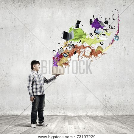 Young boy splashing colorful paint from bucket