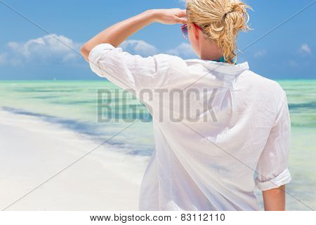 Woman on the beach in white shirt.