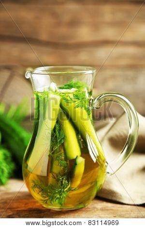 Glass ewer with fresh organic cucumber water on wooden table
