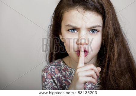 Young beautiful Little girl  has put forefinger to lips as sign of silence