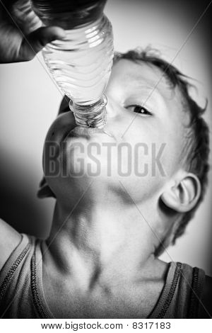 Ugasić pragnienie. Chłopiec pije wodę mineralną z butelki