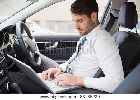 Businessman working in the drivers seat in his car
