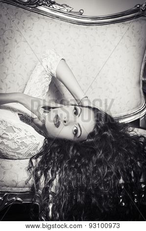 Pretty model girl sitting on victorian sofa posing for camera