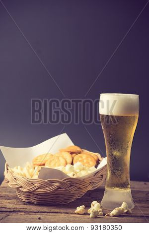 Glass of light beer and popcorn vintage color