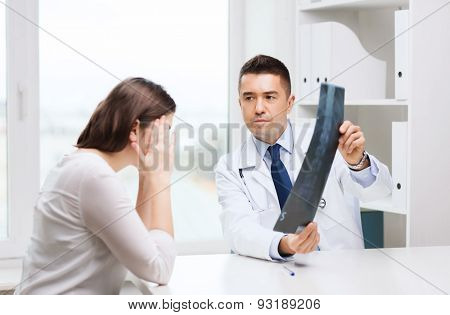 healthcare, surgery, rontgen, people and medicine concept - smiling male doctor in white coat with laptop computer looking at x-ray in medical office