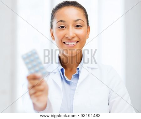 healthcare and medical concept - african doctor with blister packs of pills