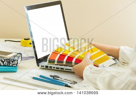 designer's working table - dhands of esigner holding colour guide, copy space on emptyy screen