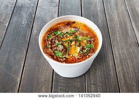 Japanese cuisine hot food delivery - miso soup at gray wooden background in white plastic plate