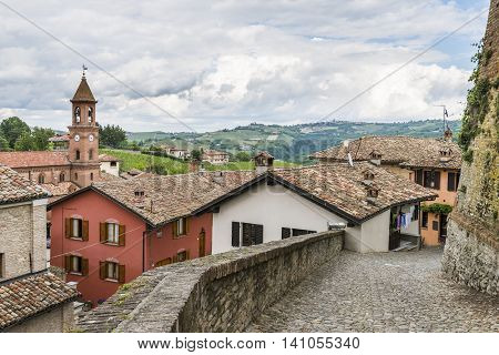 Picturesque street in Serralunga d'Alba Piedmont Italy with roses colored houses and church.