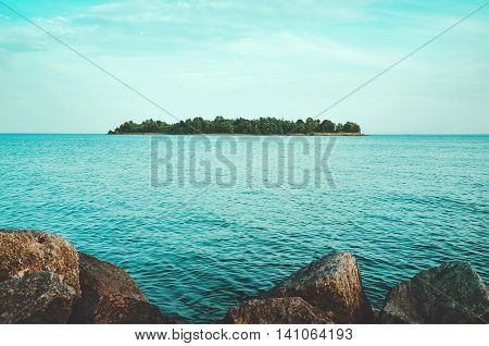 Summer island with green forest blue sky water on the Baltic sea coast with big stones. Landscape view on the Gulf of Finland Kronstadt Saint-Petersburg. Europe vacation travel tourist destinations in Russia.