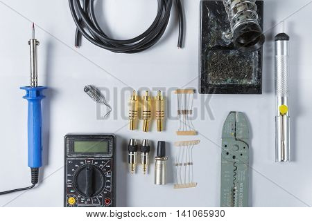 Top view of Tools for home electrical repair - soldering iron cable solder tin soldering iron stand resistor Jack 3.5 xlr rca diode pliers scissors cable stripper multimeter. Flat lay