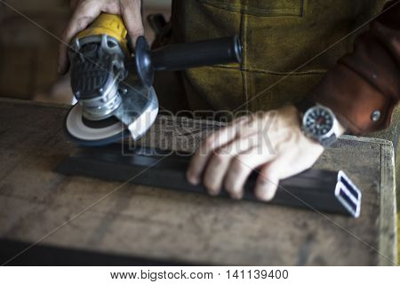 Woodworker grinding metal support structure for table.