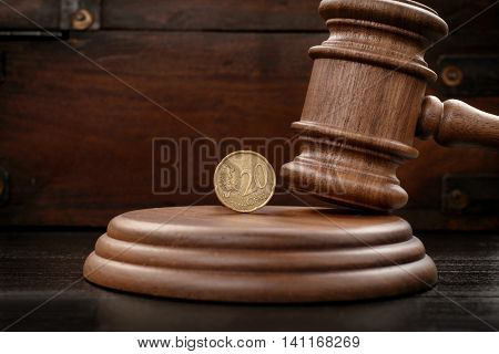 Judge gavel closeup with twenty eurocents on brown wooden background