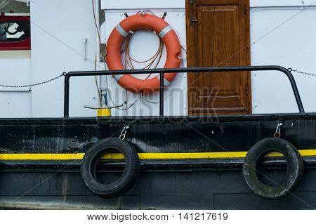 Side view of an old steel ship with lifebuoy in harbor.