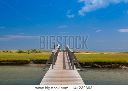 Walkway to the dunes wooden walkway extends over marshland toward the distant dunes and ocean In Sandwich Cape Cod Massachusetts USA