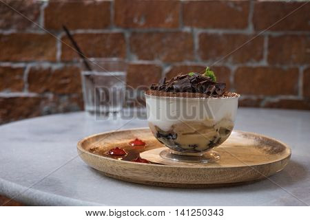 chocolate banana mousse in glass or plastic cupcake on wooden tray and brown brick wall garnish with mint leaf