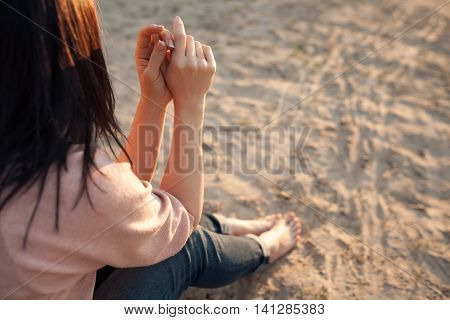 bootless woman sitting on beach at sunset; barefoot female on sand;