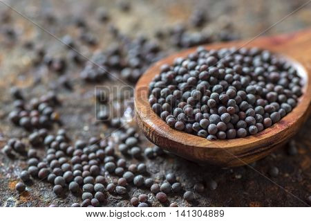 Brown Mustard Seeds in wooden spoon on texture background