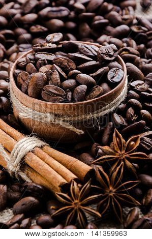 coffee beans in a wooden cup with cinnamon sticks and star anise
