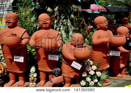 Chiang Mai Thailand - December 21 2012: Terra cotta statues of bespectacled monks holding alms bowls abound in the gardens at Wat Tha Ka Rong