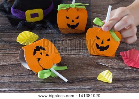 The Child Create A Greeting Packaging For Candy On Halloween Pumpkin Paper. Packing Gift Paper Pumpk