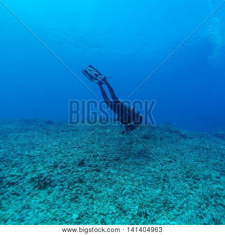 Diver man going deep in blue Bali island