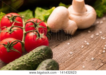 Fresh red tomatos cocumbers and mushrooms lying on the wooden table