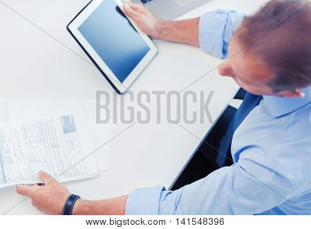 business, office, school and education concept - businessman with tablet pc and papers in office