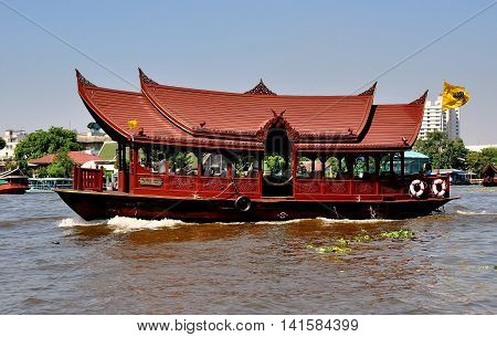 Bangkok Thailand - January 14 2013 The Mandarin Oriental Hotel's wooden ferry transfer boat with Thai-style roofs and ornate grill work panels on the Chao Praya River *