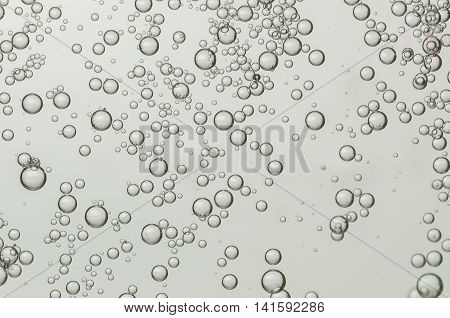 Many small light air bubbles soar over a grey background