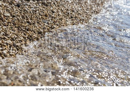 Sea wave on pebble beach in summer