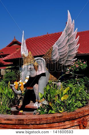 Chiang Mai Thailand - December 29 2012: Statue of a winged elephant with floral offerings left on its tusks at Wat Chomphu